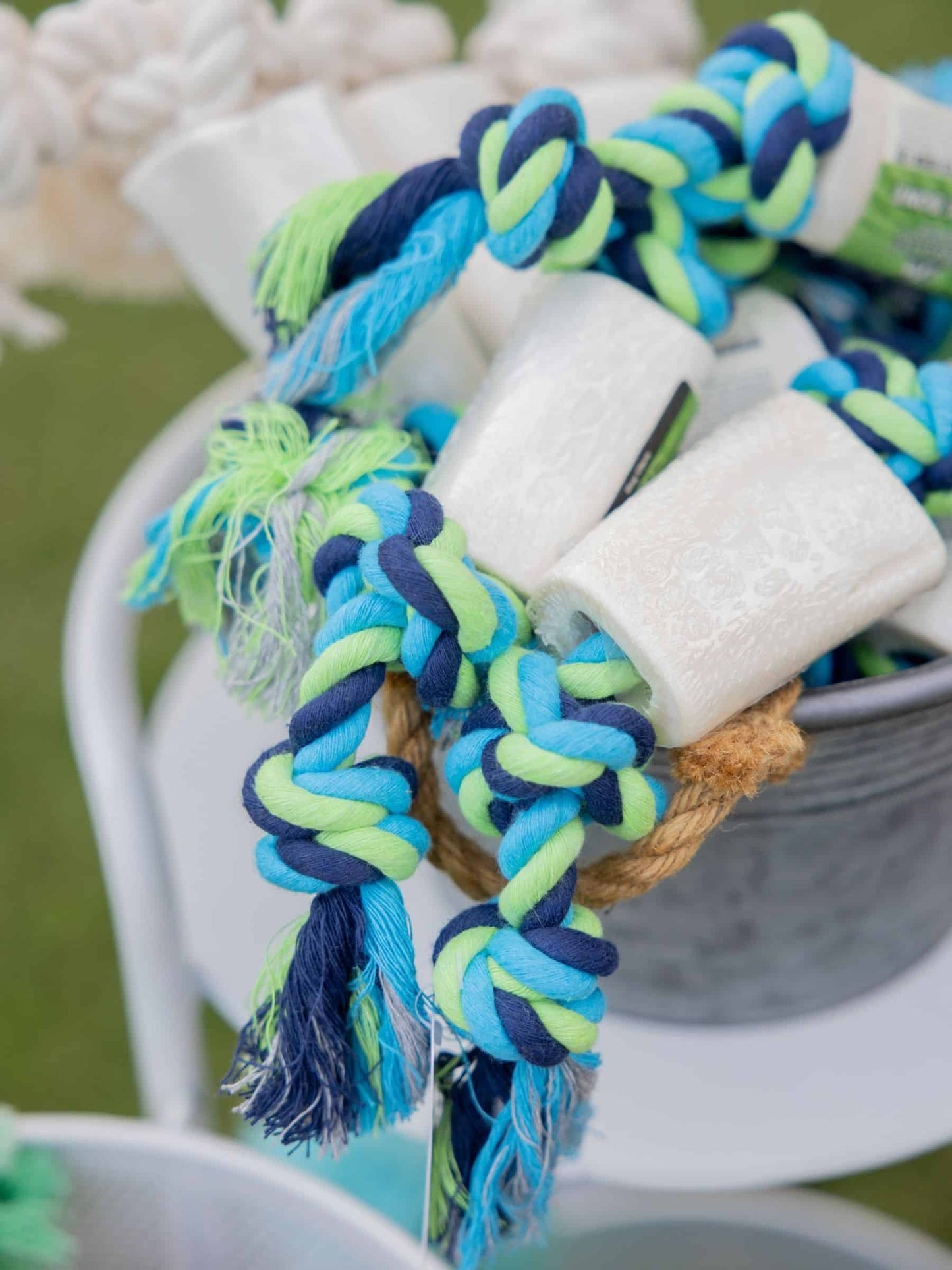 Colorful braided rope dog toys going through a beef bone sitting in a metal basket