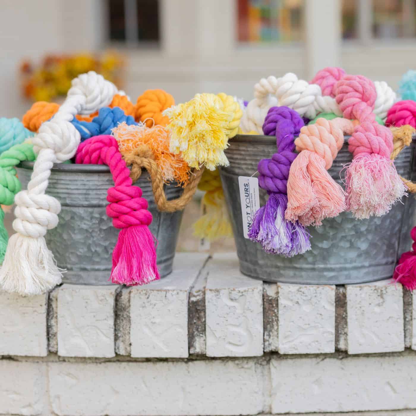 Galvanized bucket filled with colorful knotted cotton rope dog toys in blue, green, yellow, orange, pink, and turquoise.