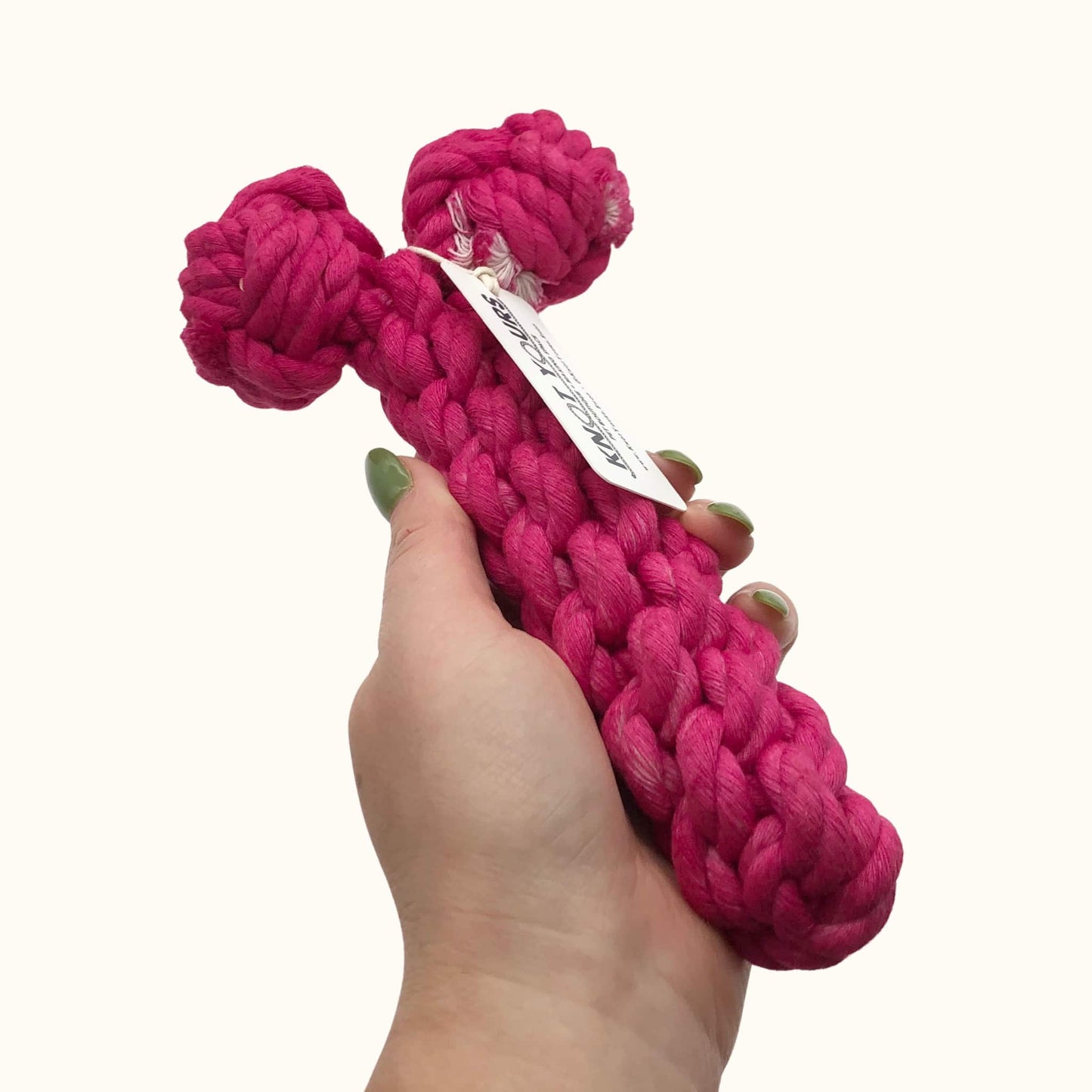 Pink rope dog toy shaped like a penis, part of the Dick Toys collection, with two knotted ends for durability. Held in hand for size reference.