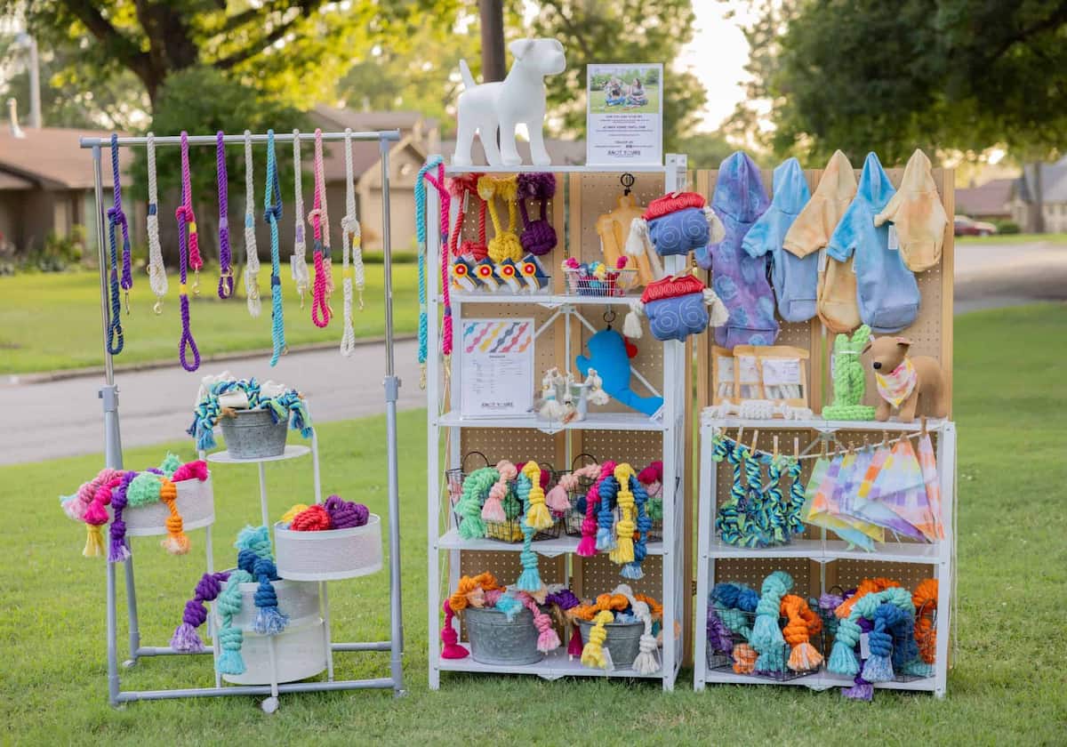 Display of colorful handmade dog items on shelves outdoors