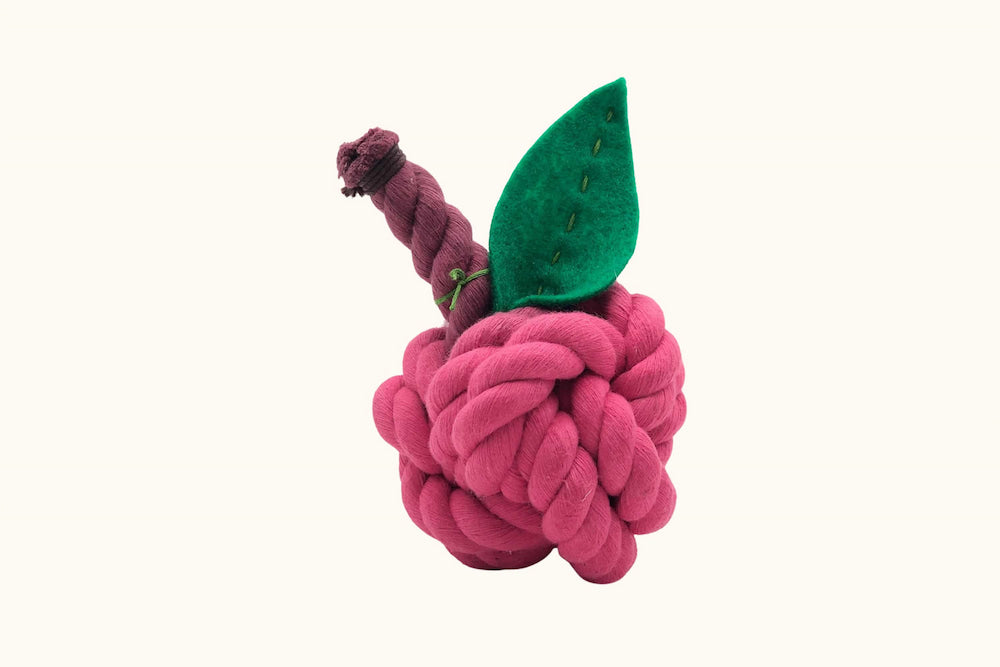 Pink knotted dog toy resembling a berry with a green leaf on a white background