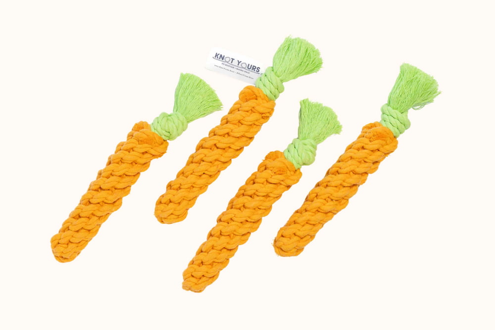 A hand holds a vibrant hot pink rope bone dog toy with a Knot Yours tag, showing product size.