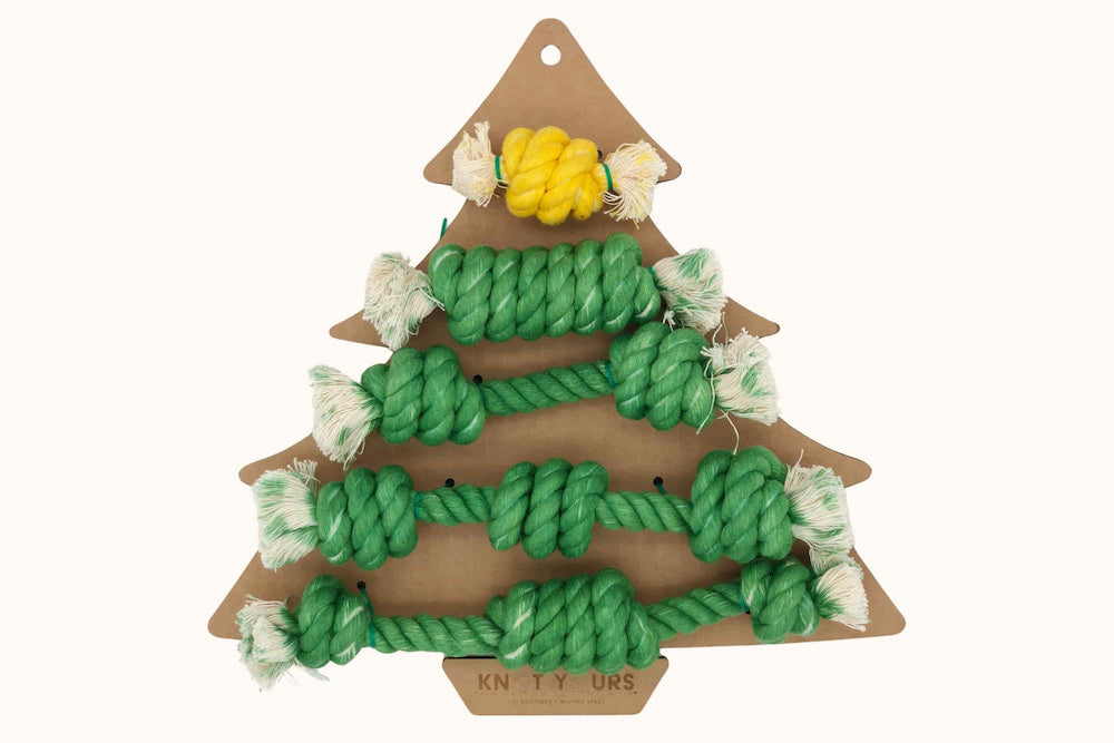 A set of green rope dog toys arranged on a cardboard Christmas tree backing