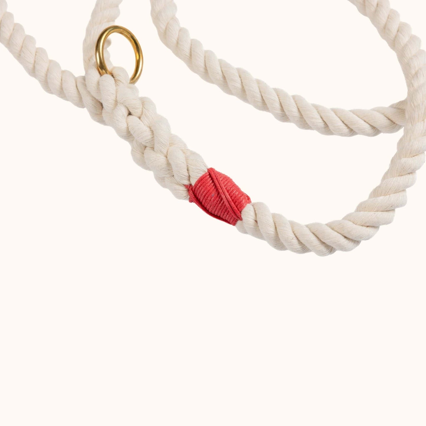 Close-up of a handmade natural cotton dog leash with red whipping and braided rope.