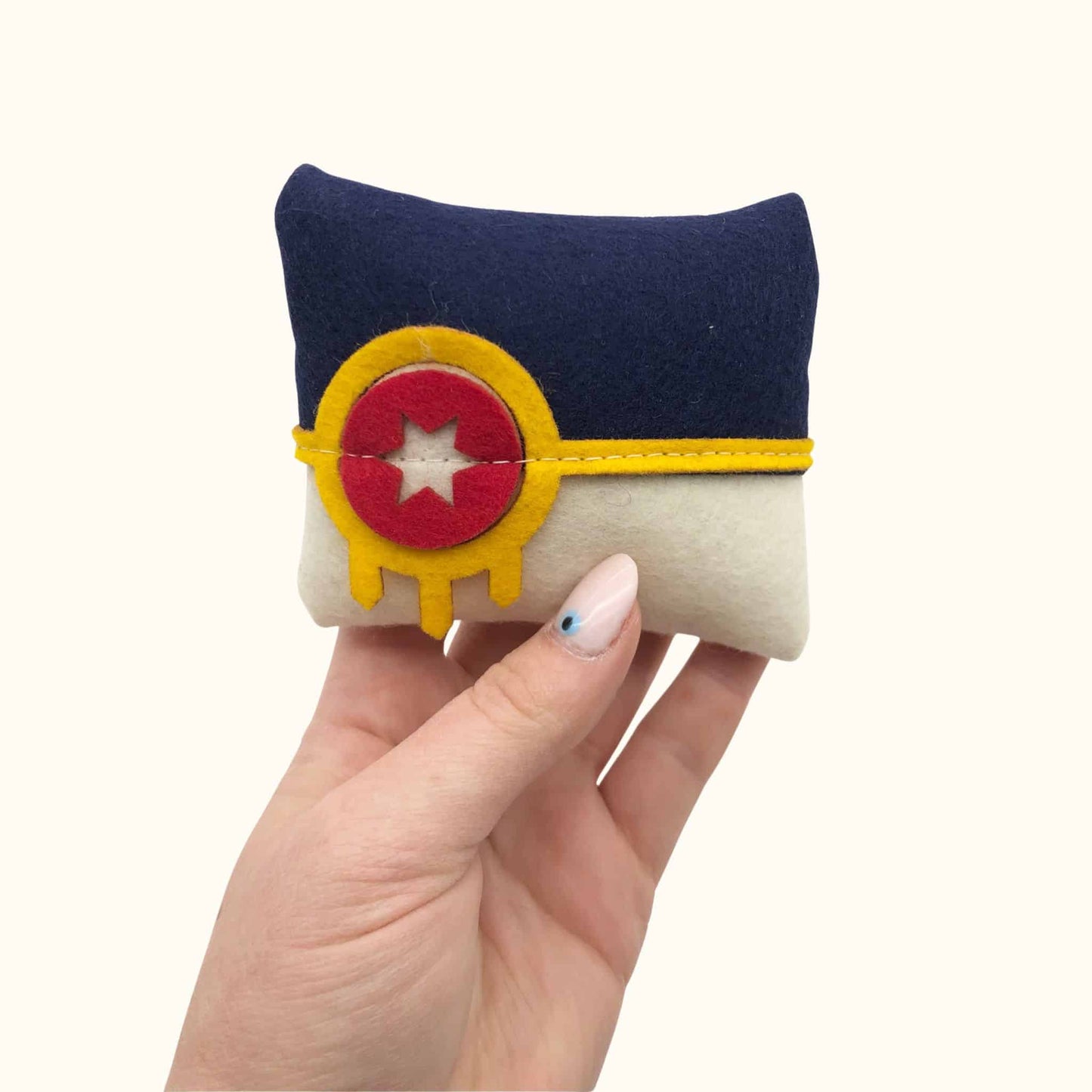 Hand holding Tulsa Flag Catnip Pillow, a soft felt catnip pillow in blue, white, and yellow design for playful cats.