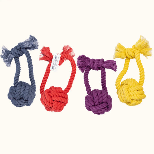 Four Giant Monkey Knot dog toys in navy, red, purple, and yellow, lined up side by side to show the full color range.