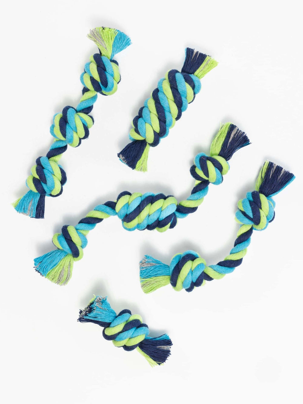 Flat lay of six colorful rope toys for small dogs, each tied in a different knot style including snitch, barrel, tube, and other playful shapes for puppies.