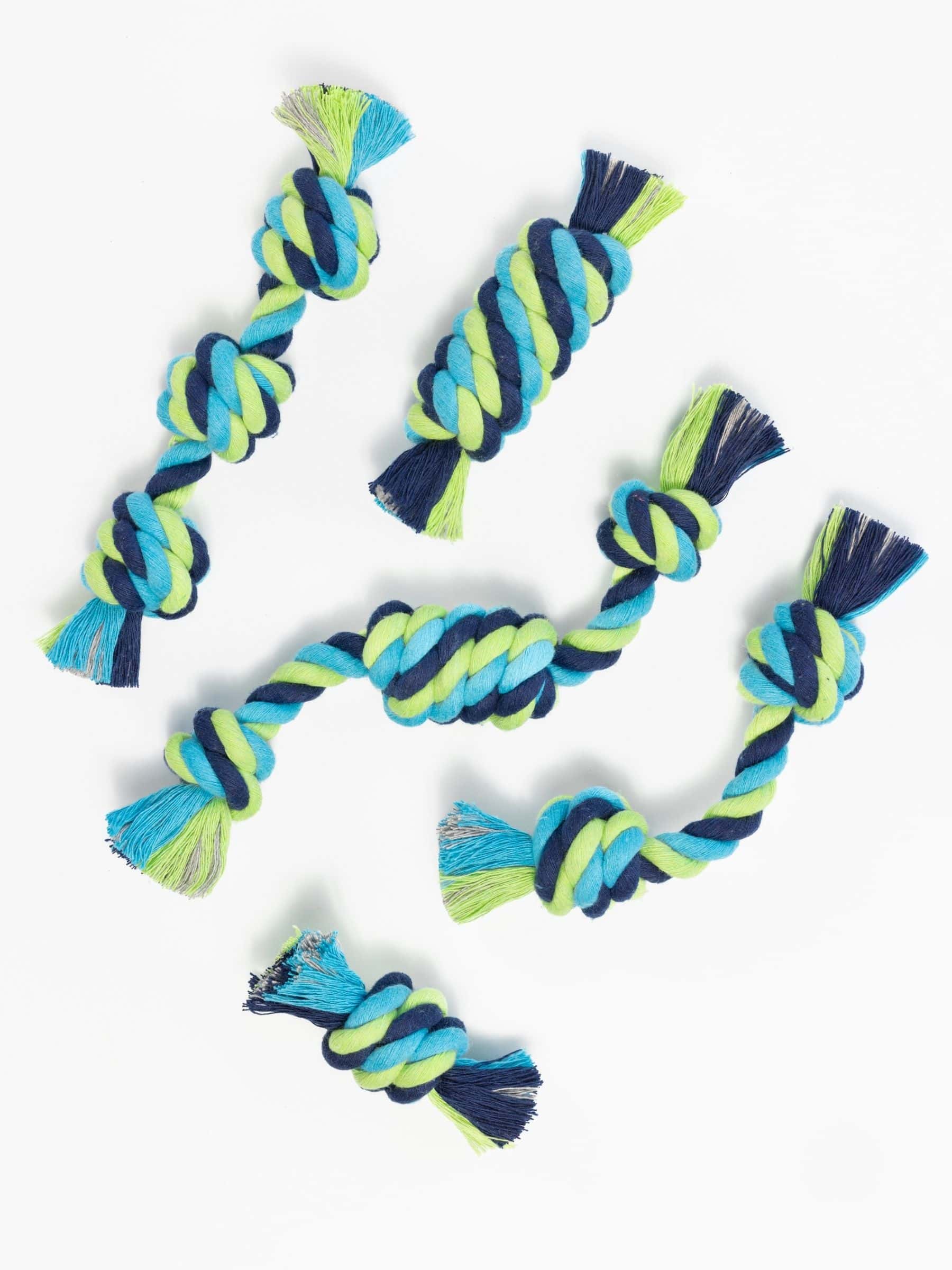 Flat lay of six colorful rope toys for small dogs, each tied in a different knot style including snitch, barrel, tube, and other playful shapes for puppies.