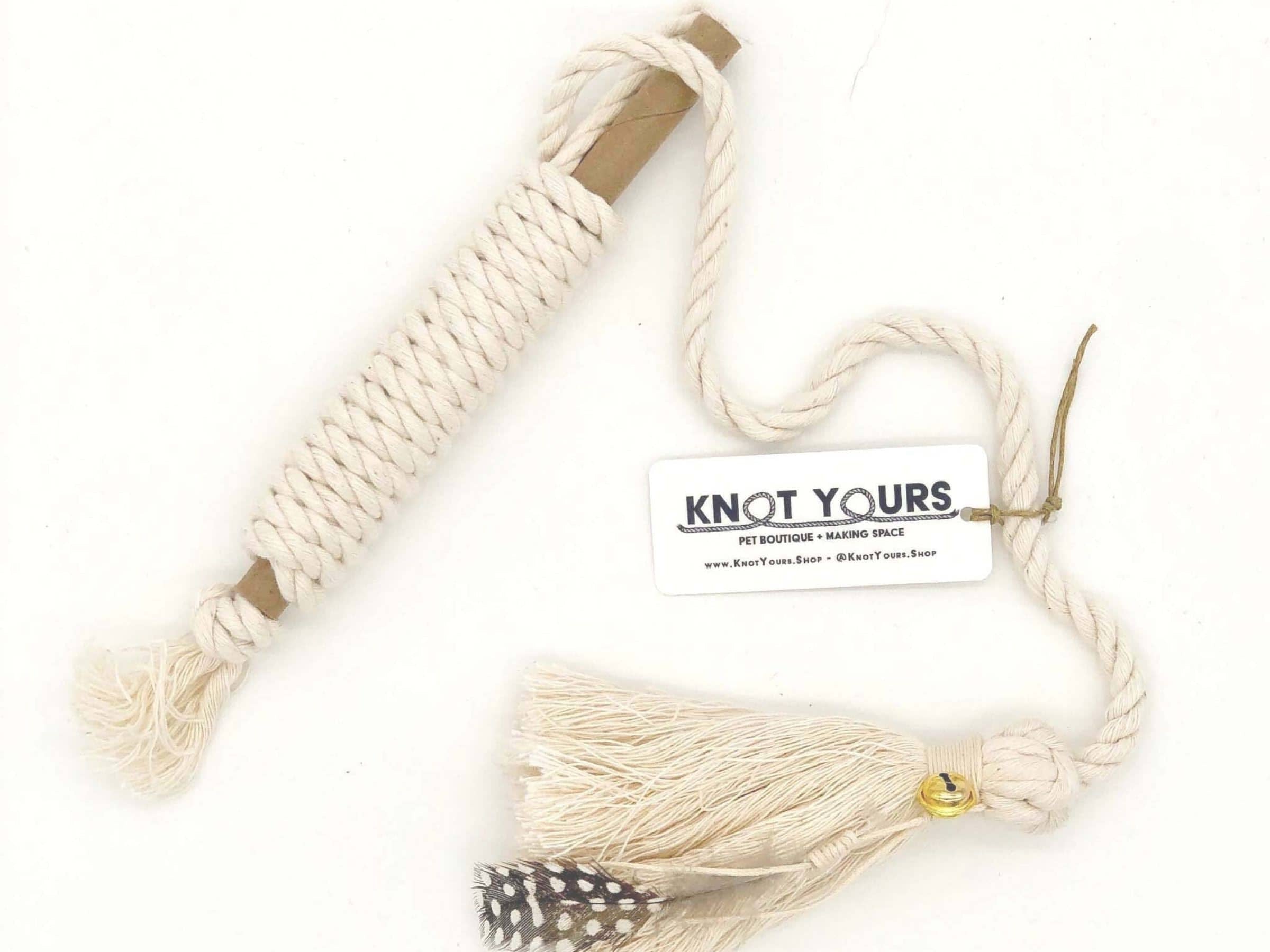 Beige cat rope toy with tassel and 'Knot Yours' label on a white background
