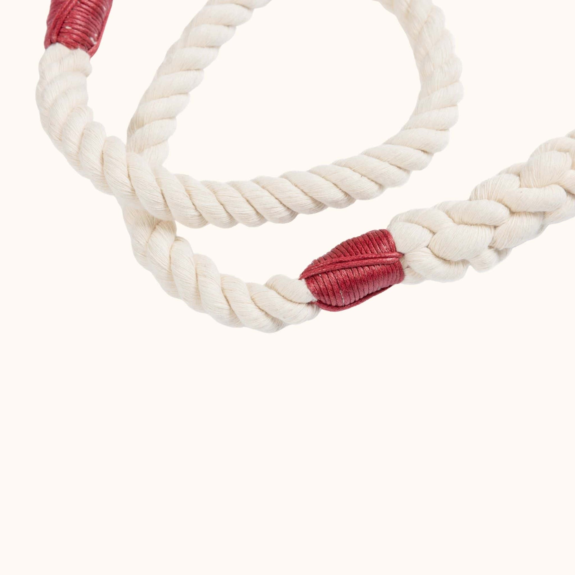 Natural handmade rope leash with red whippings on a white background