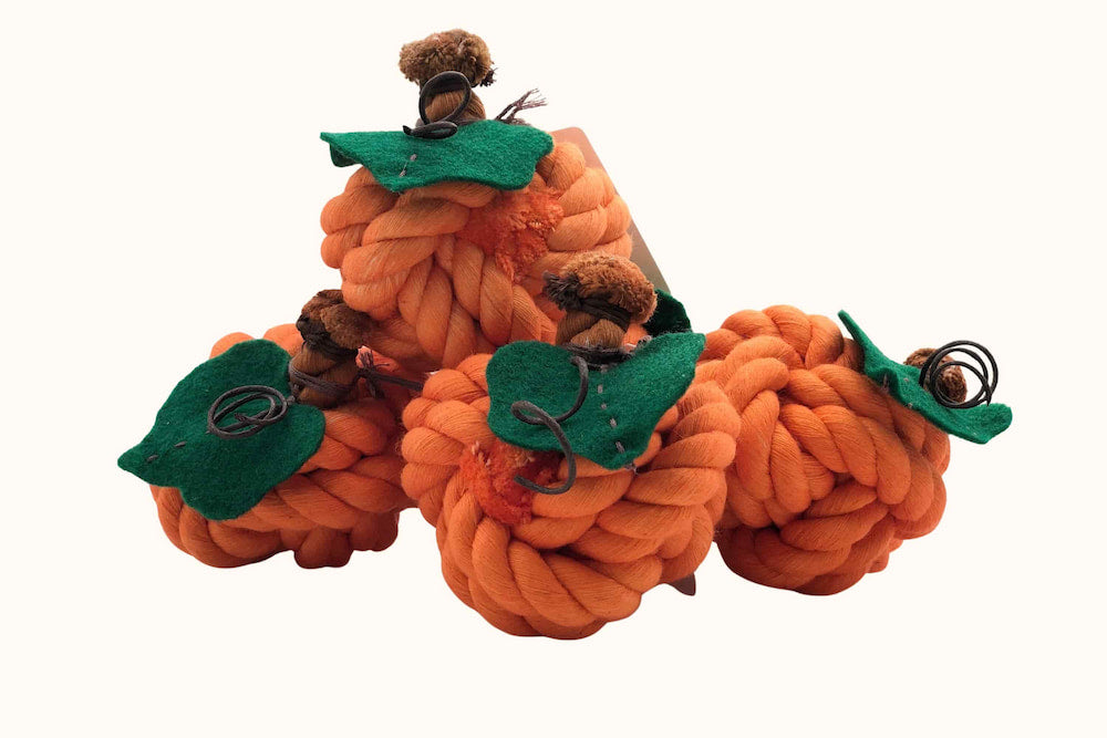 Multiple orange pumpkin-shaped rope toys with green felt leaves and brown stems.