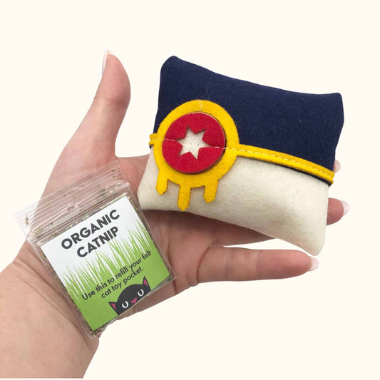 Hand holding Tulsa Flag Catnip Pillow in blue, white, and yellow felt design with included organic catnip refill pack, fun catnip toys for cats.